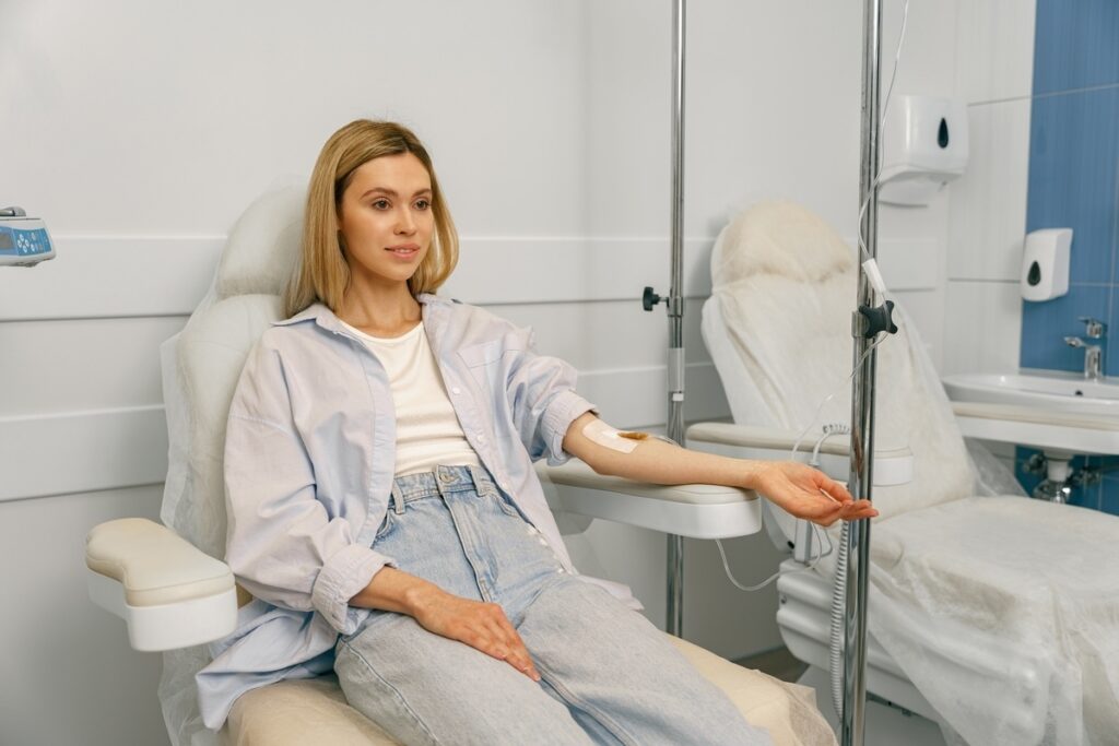 IV hydration for fatigue showing a woman receiving intravenous fluids while resting in a medical clinic.