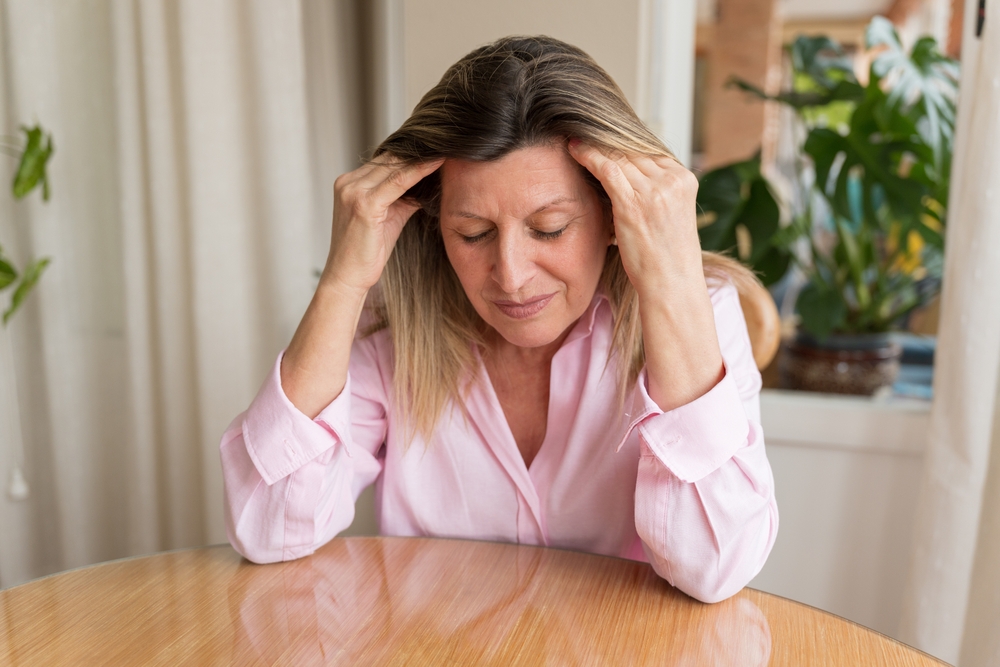Middle-aged woman experiencing mood swings and brain fog while resting her head on her hand
